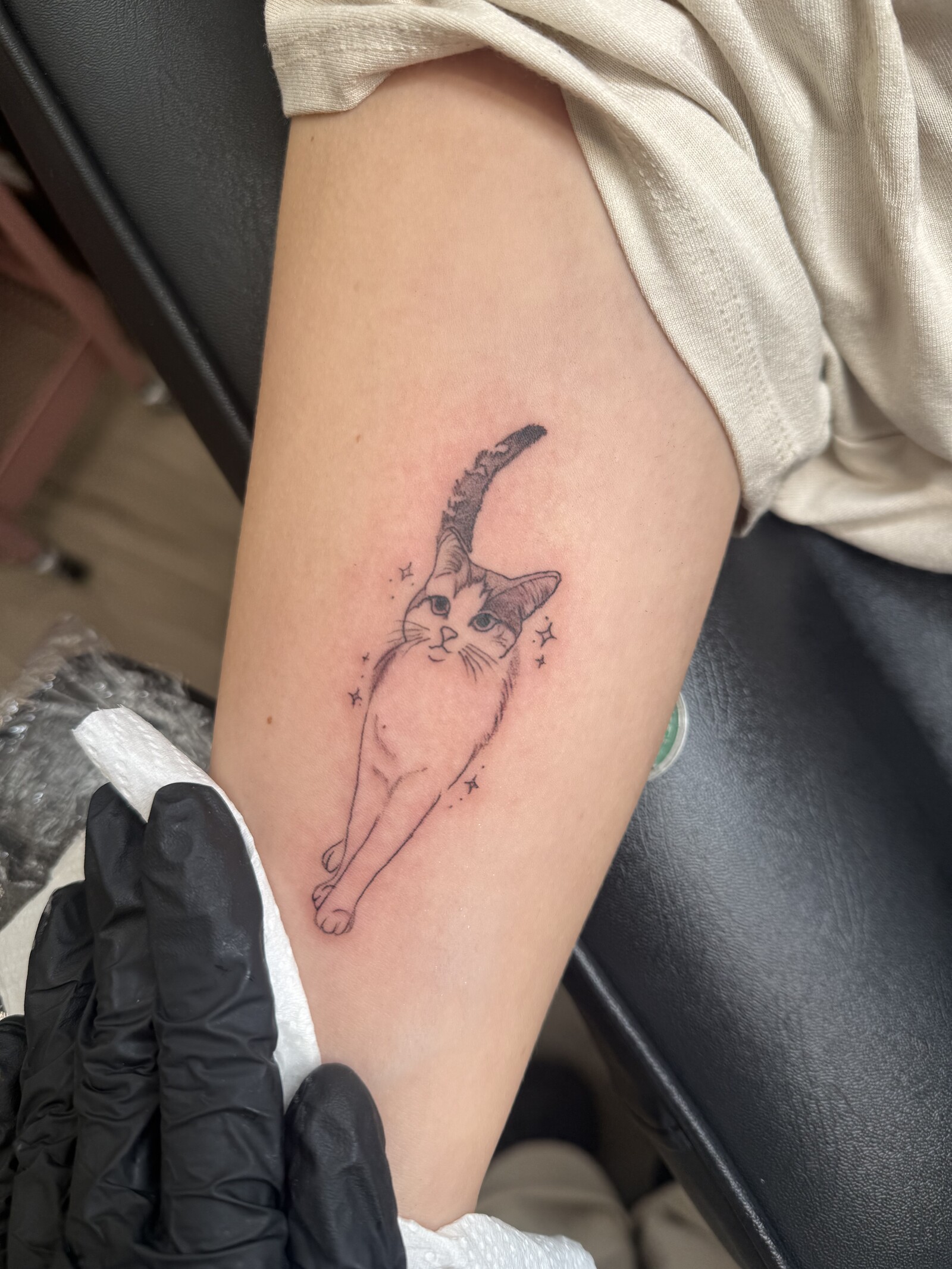 Fine-line illustrated animal tattoo on an upper arm