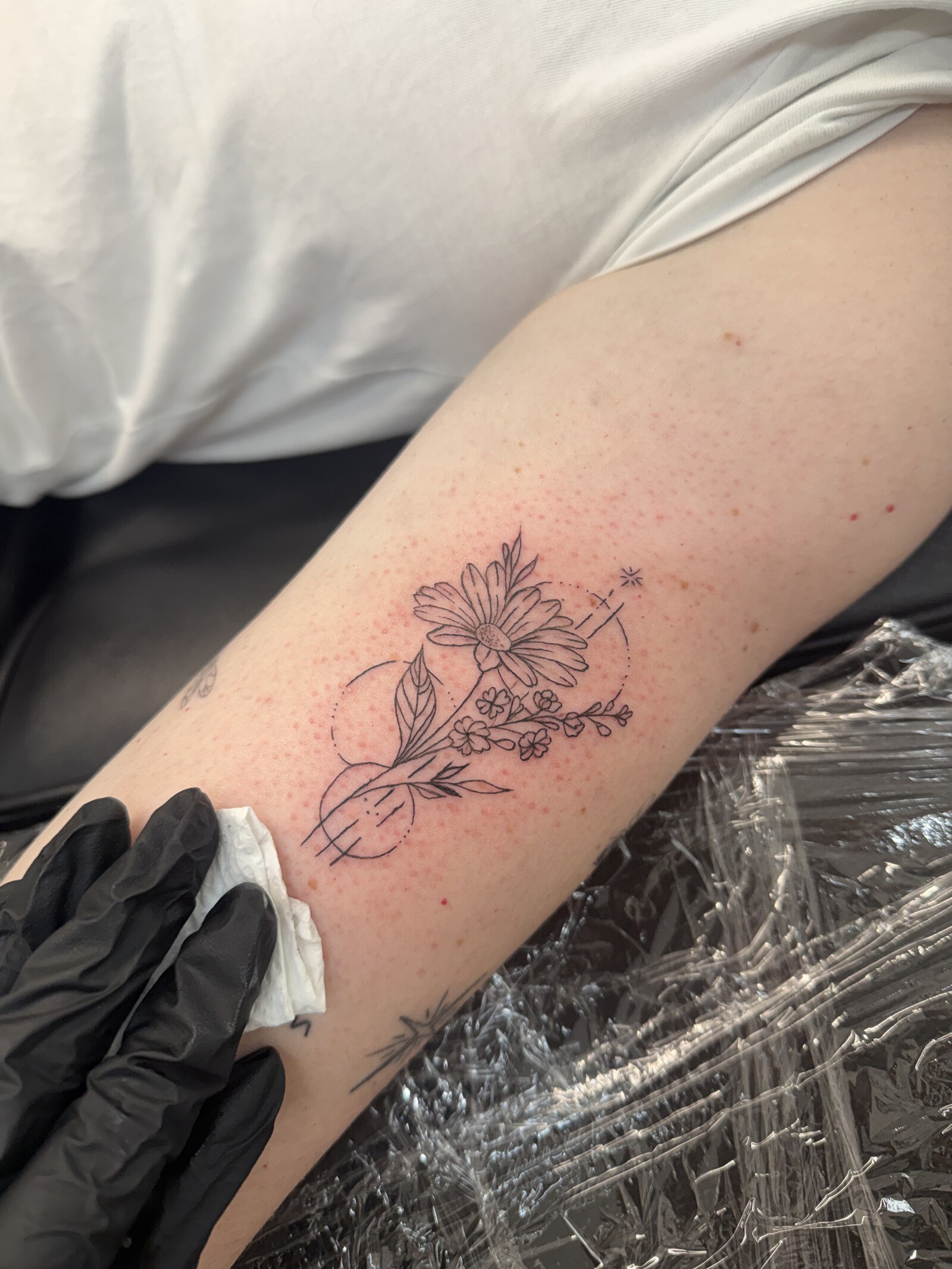 Fine-line floral tattoo on an upper arm