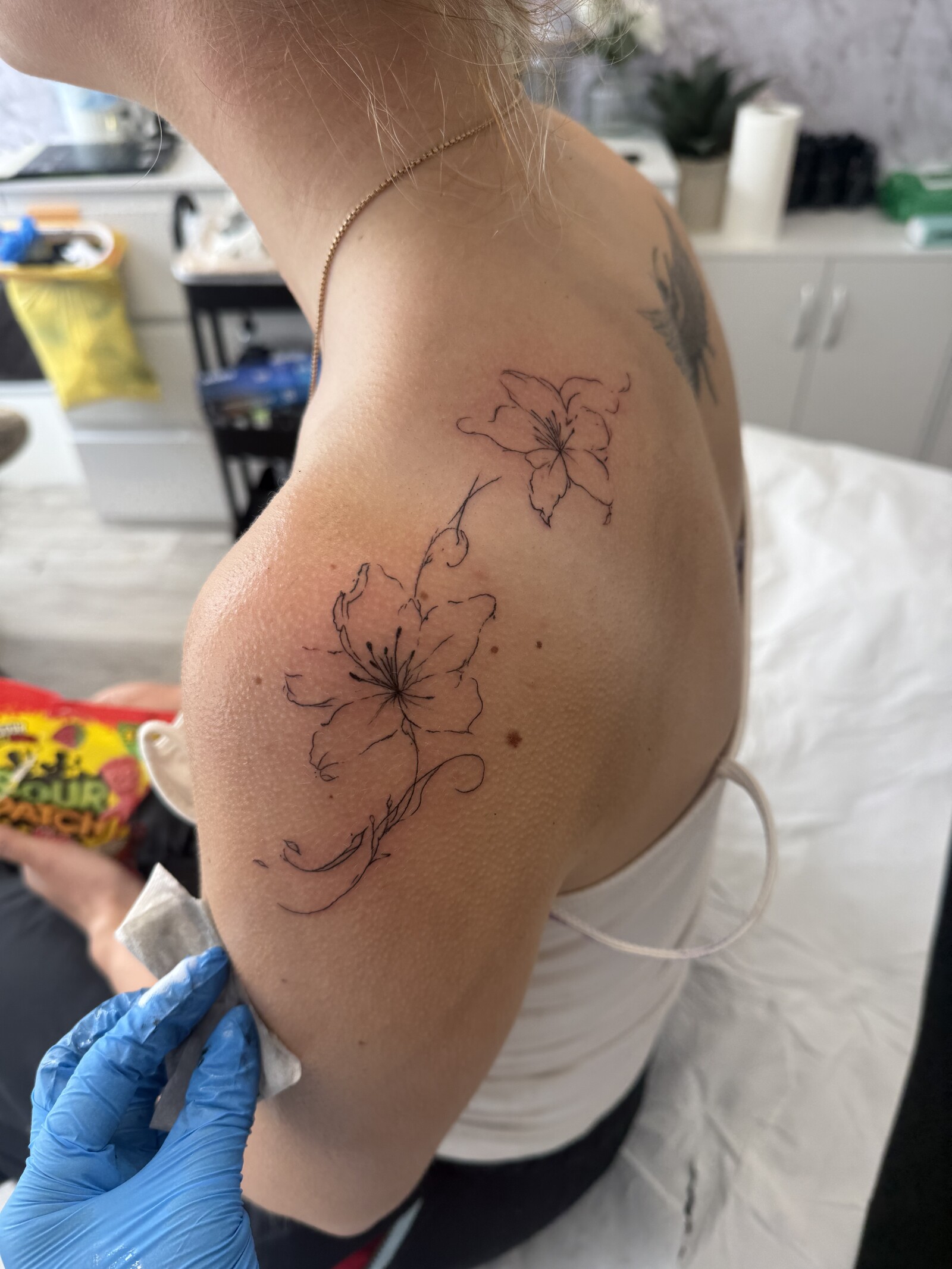 Fine-line floral tattoo across an upper arm