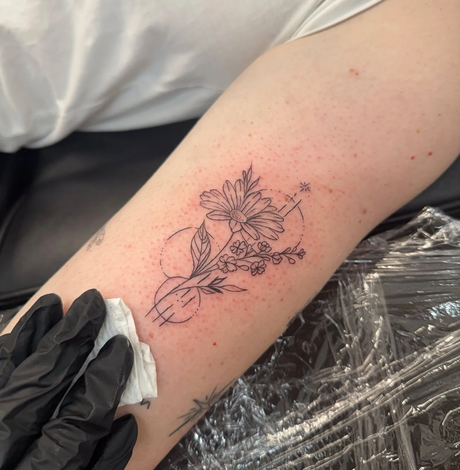 Fine-line floral tattoo placed on a client’s upper arm